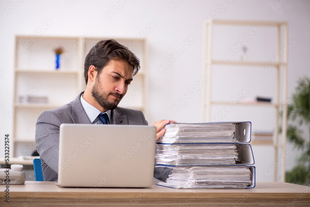 Young male employee and too much work in the office Young male employee and too much work in the office