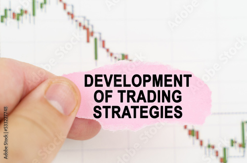 Against the background of the quote chart, a man holds a sign with the inscription - development of trading strategies