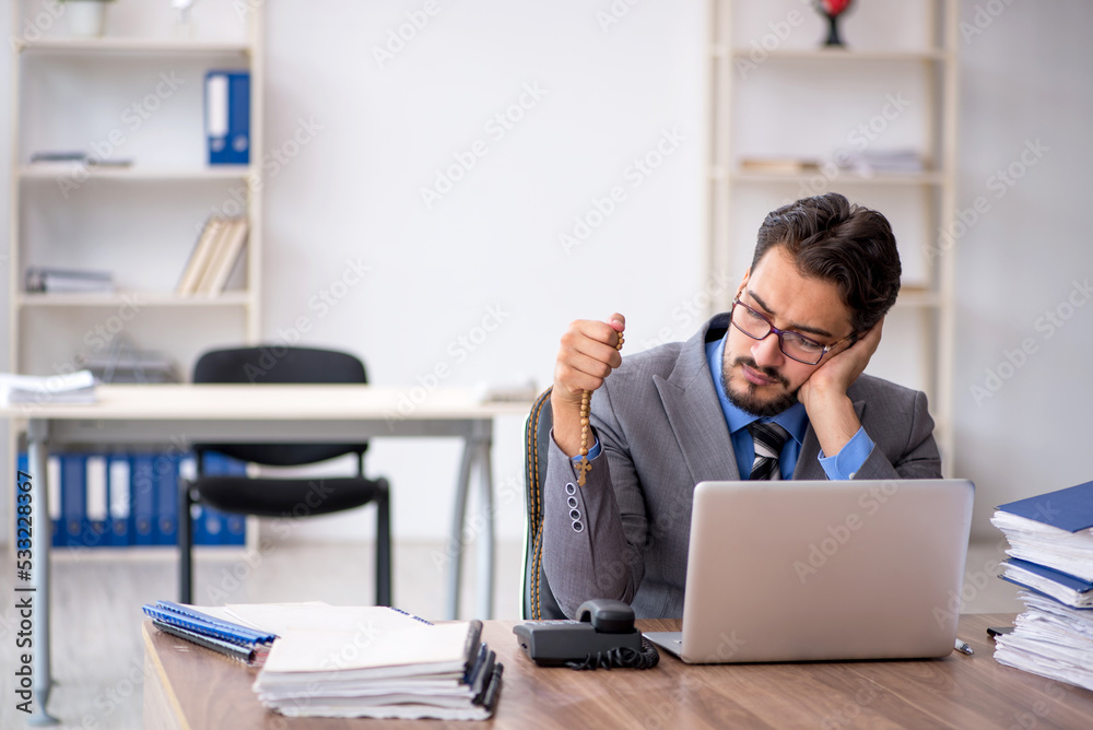 Fototapeta premium Young male employee unhappy with excessive work in the office