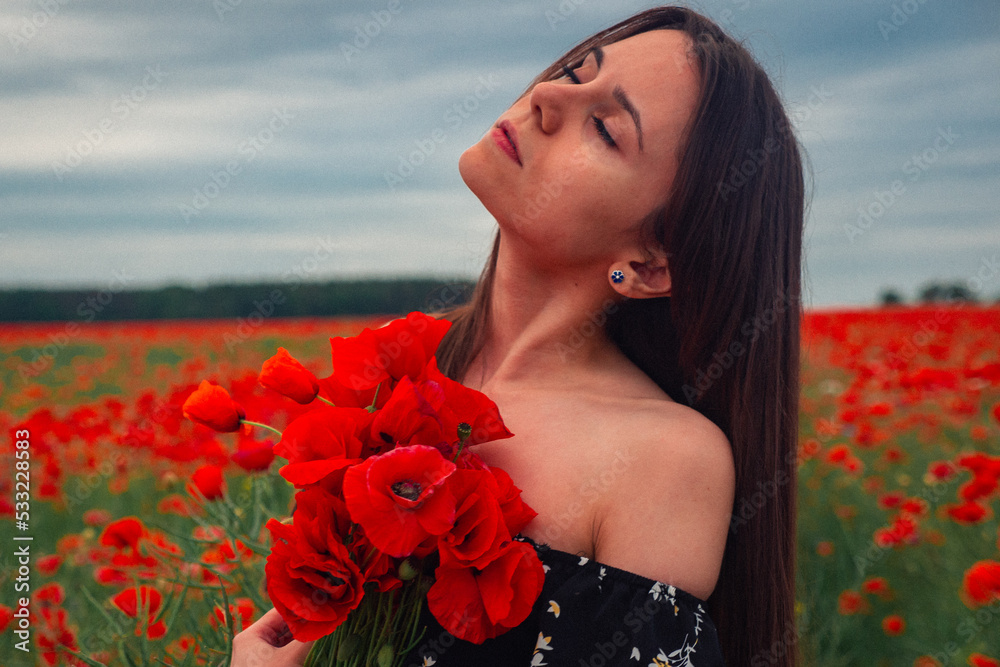 Naklejka premium Cute sexy beautiful woman in a red field of poppy flowers. Brunette girl long flowing hair. Freedom concept and tenderness