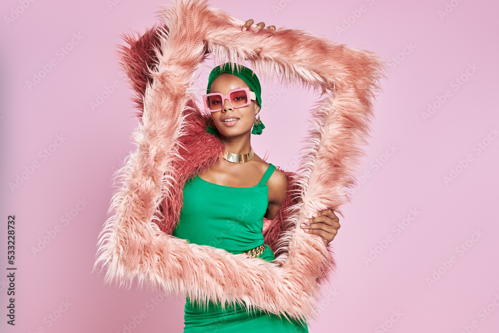 Attractive African woman in traditional headwear holding a fluffy frame against yellow background Attractive African woman in traditional headwear holding a fluffy frame against yellow background
