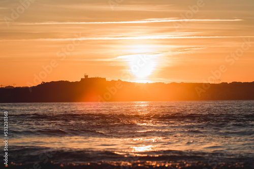 Spectacular panoramic view of a castle on the horizon on the mountain over the sea at sunset during a surf and travel week experience in Somo  Cantabria  Spain 