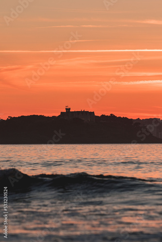 silhouette of a castle on the edge of the mountain at sunset over the sea during a surf and travel week experience in Somo, Cantabria (Spain)