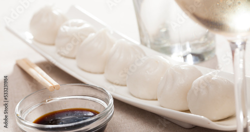 Dim sum dumplings with soy sauce on white plate