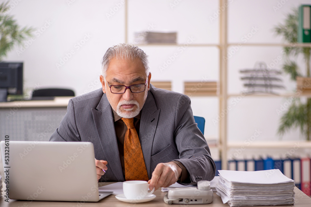 Old male employee drinking coffee during break Old male employee drinking coffee during break