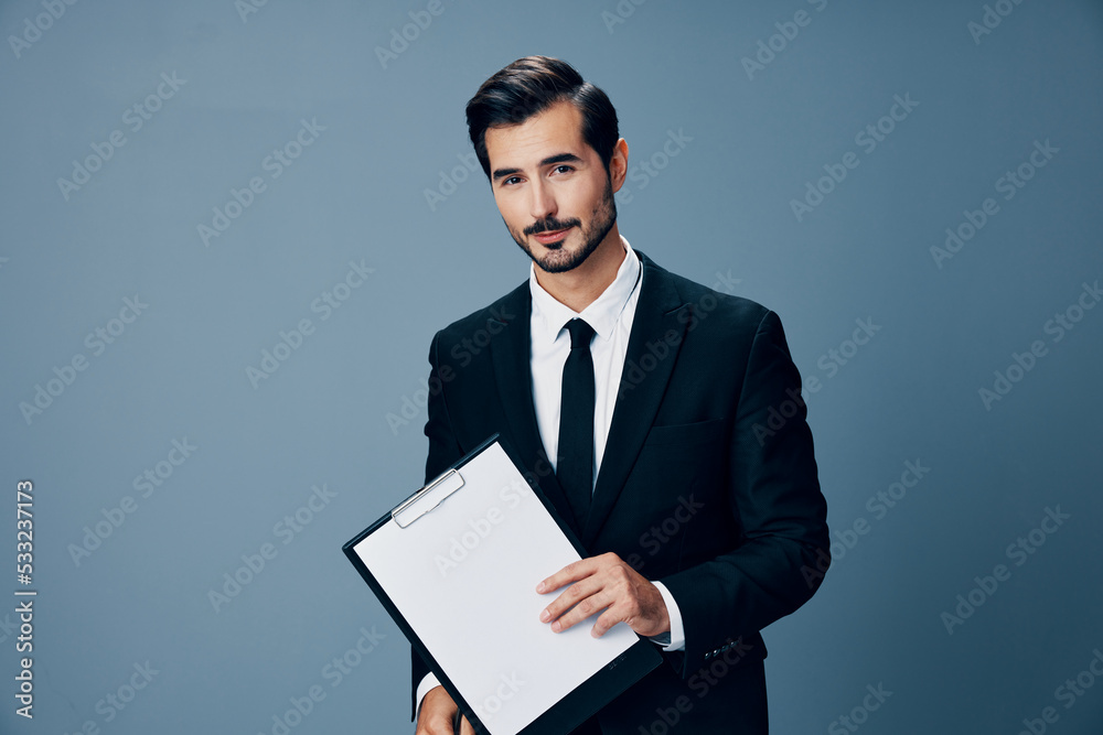 Portrait of a business man in a stylish suit smile with tie beautiful face on a blue isolated background with a tablet in his hands. Business concept young businessman startup copy place Portrait of a business man in a stylish suit smile with tie beautiful face on a blue isolated background with a tablet in his hands. Business concept young businessman startup copy place