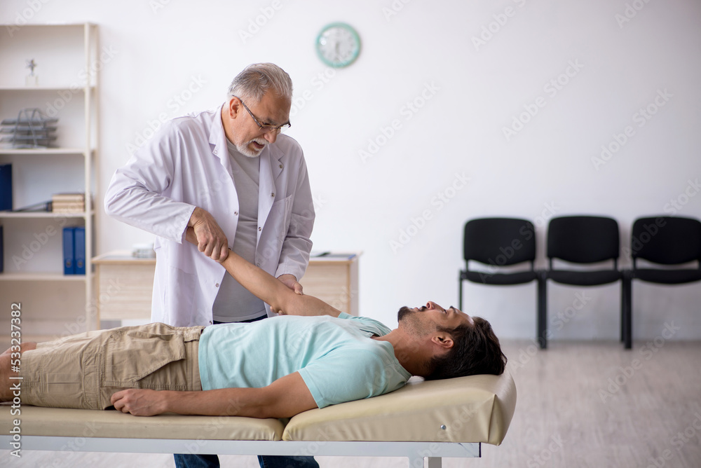Fototapeta premium Young male patient visiting old male doctor