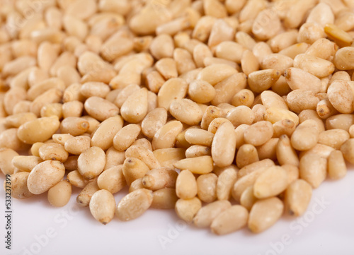 Healthy snack. Shelled seeds of pine nuts (pignolis) on white background..