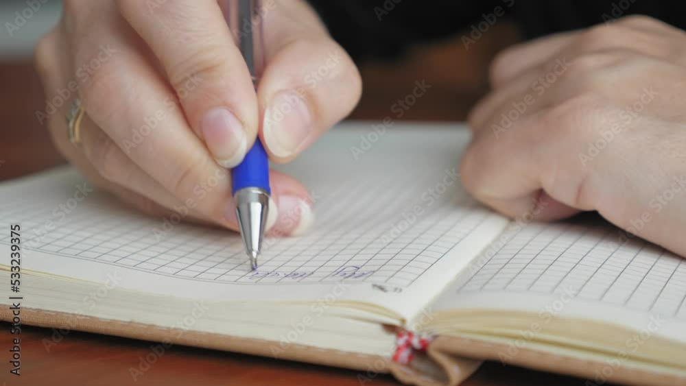 A woman writes with a pen in a notebook, close-up. The girl makes a to-do list for the day. Caucasian woman writes goals today. A woman writes with a pen in a notebook, close-up. The girl makes a to-do list for the day. Caucasian woman writes goals today.