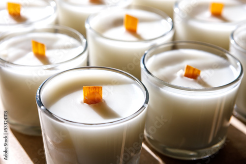 A row of scented candles illuminated by the bright sun stands on the table.