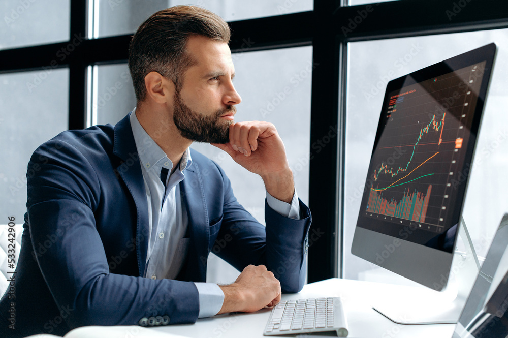 Pensive concentrated clever successful caucasian male stock investor, broker, sits at his work desk, looks at computer, focused analyzes risks and prospects, rise or fall of cryptocurrency coin Pensive concentrated clever successful caucasian male stock investor, broker, sits at his work desk, looks at computer, focused analyzes risks and prospects, rise or fall of cryptocurrency coin