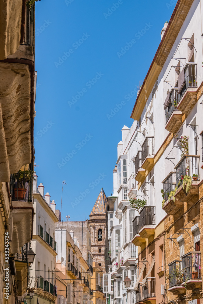 Colorful street with balconies and tower of San Lorenzo Parish church in the background, Cádiz SPAIN