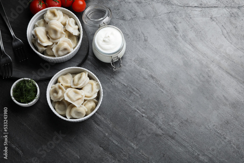 Tasty dumplings in bowls served on grey table  flat lay. Space for text