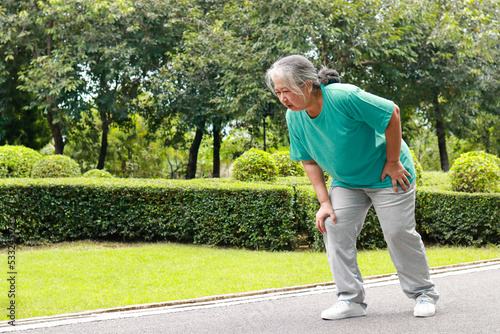 elderly women jogging in the park She has pain in her right knee. Concept of health care to be healthy in retirement age. bone disease in the elderly