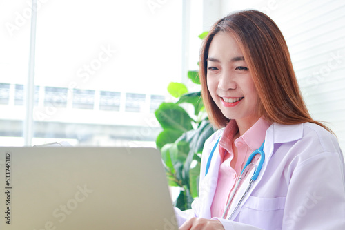 Asian female doctor sitting in office use a laptop computer Online video call talks to patients remotely. online medical concept Hospital medical services