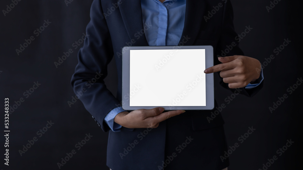 Close up of business woman standing and holding tablet blank white screen on black background Close up of business woman standing and holding tablet blank white screen on black background