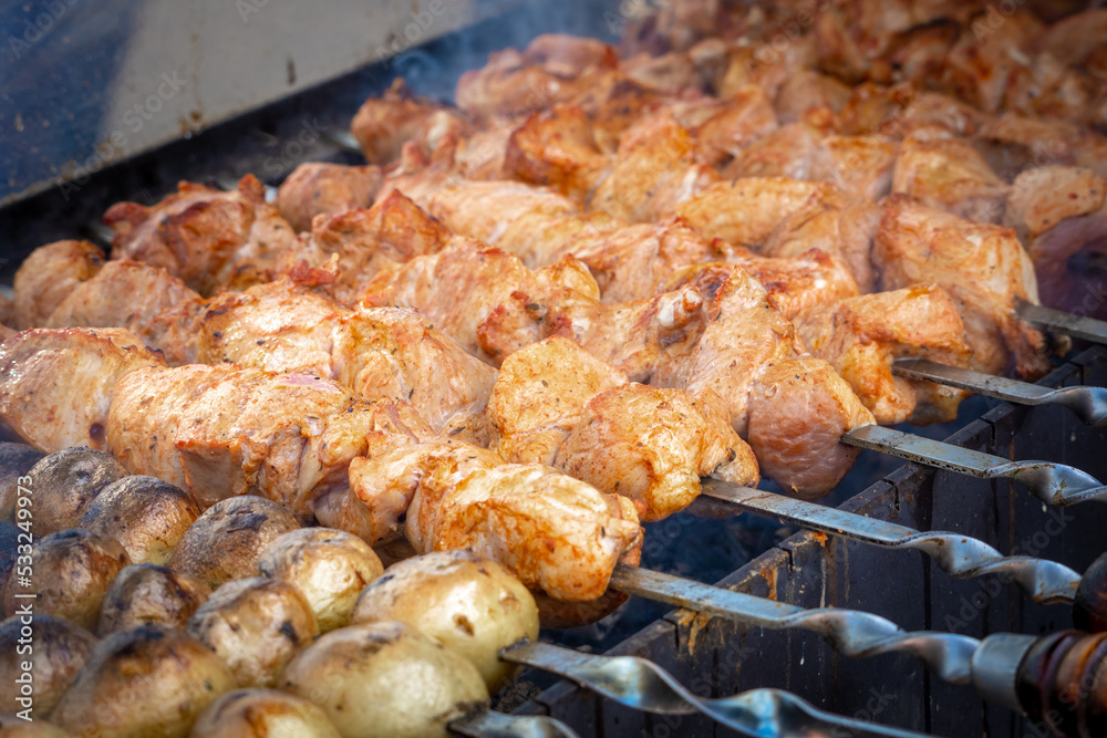 Outdoor street food. Marinated pork shashlik and potatoes roasted on a charcoal grill. A traditional Caucasian dish Outdoor street food. Marinated pork shashlik and potatoes roasted on a charcoal grill. A traditional Caucasian dish