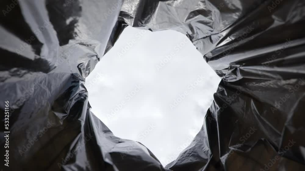 Slow motion low angle view of hand dropping plastic bottle into recycling trash container