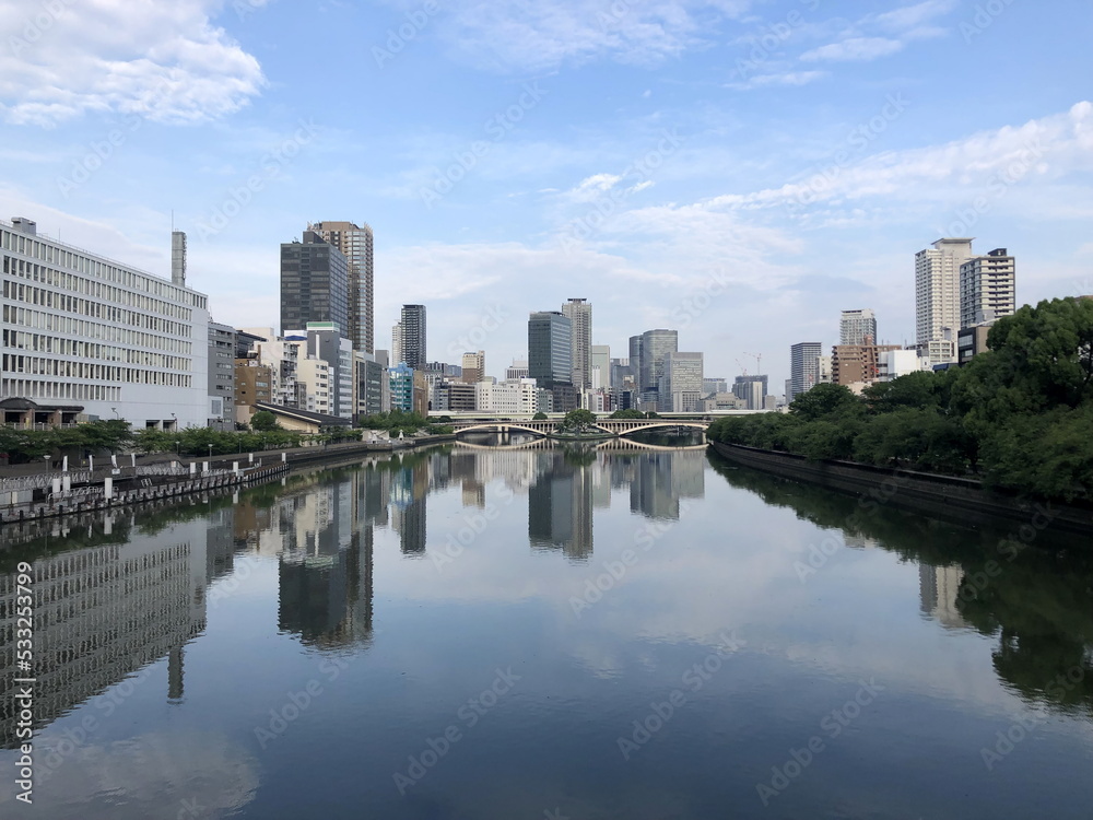 a view of downtown Osaka, Japan over the river - skyscraper cityscape and cloudy sky reflected in the river 