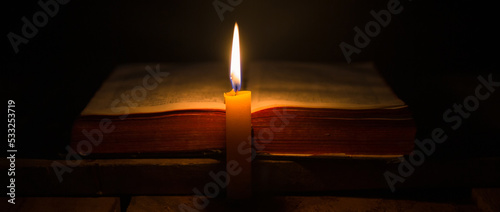 Canvas Print Light candle with holy bible and cross or crucifix on old wooden background in church