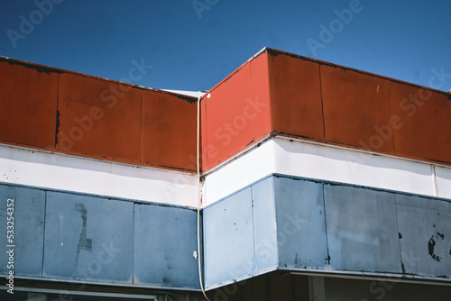 corner detail of weathered vintage red, white and blue trim of a building against the blue sky
