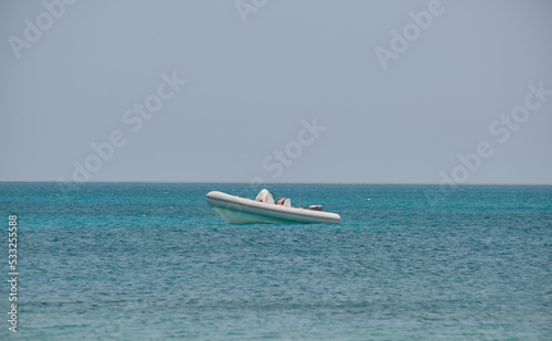 Seascape with ripple surface of blue sea water with white speedboat on anchor floating on calm waves