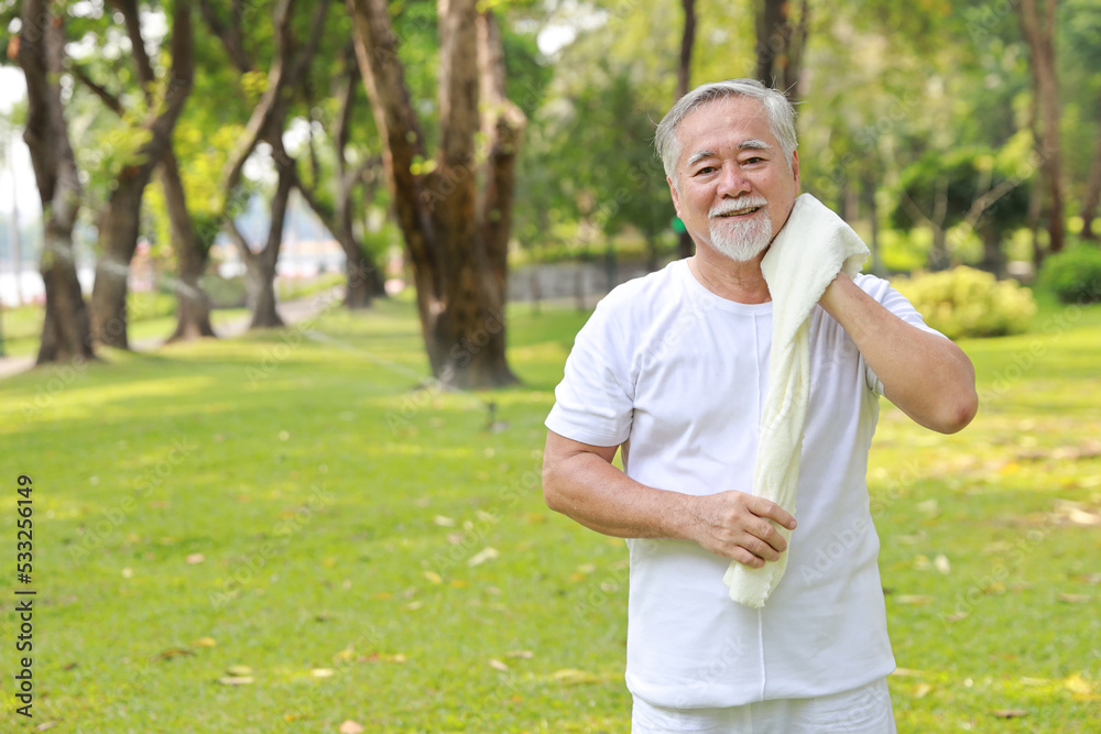 Tired heat and hot asian senior man practice yoga excercise, tai chi tranining and stretching while wipe the sweat away for healthy in park outdoor. Happy elderly outdoor lifestyle concept Tired heat and hot asian senior man practice yoga excercise, tai chi tranining and stretching while wipe the sweat away for healthy in park outdoor. Happy elderly outdoor lifestyle concept
