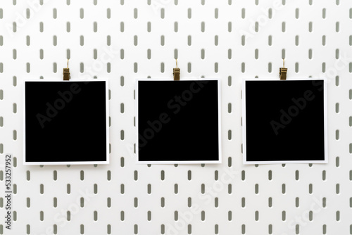Three blank photo frames with clips on peg board. Template for photography and prints