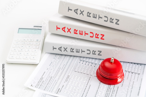 Stack of tax return folders, forms, calculator and call bell, time for tax return concept