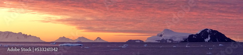Panorama of a colorful sunset  with the clouds glowing with pink light  at Cierva Cove  Antarctica