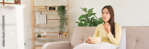 Leisure activity concept  Young woman eating popcorn while sitting on couch to watching television