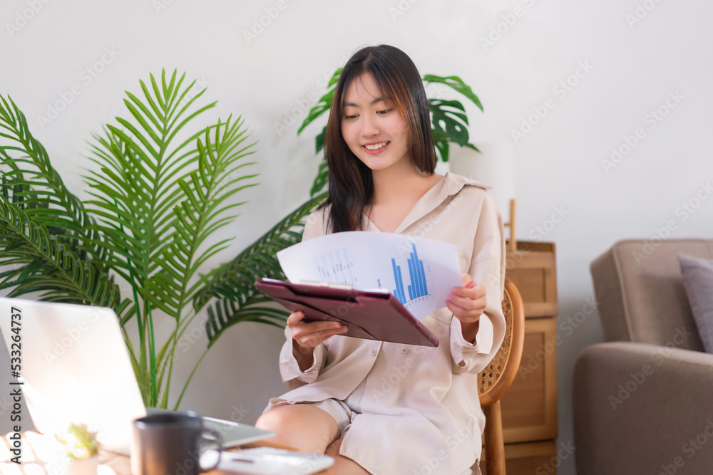 Concept of activity in living room, Asian woman reading business document while working at home Concept of activity in living room, Asian woman reading business document while working at home