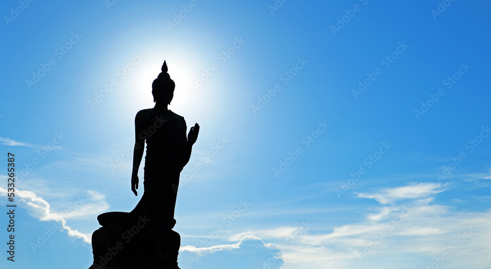 Silhouette Buddha standing statue and blue-sky background with blurred motion