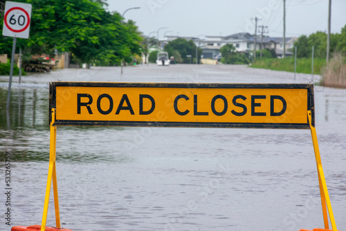 Road closed sign with flooded street beyond