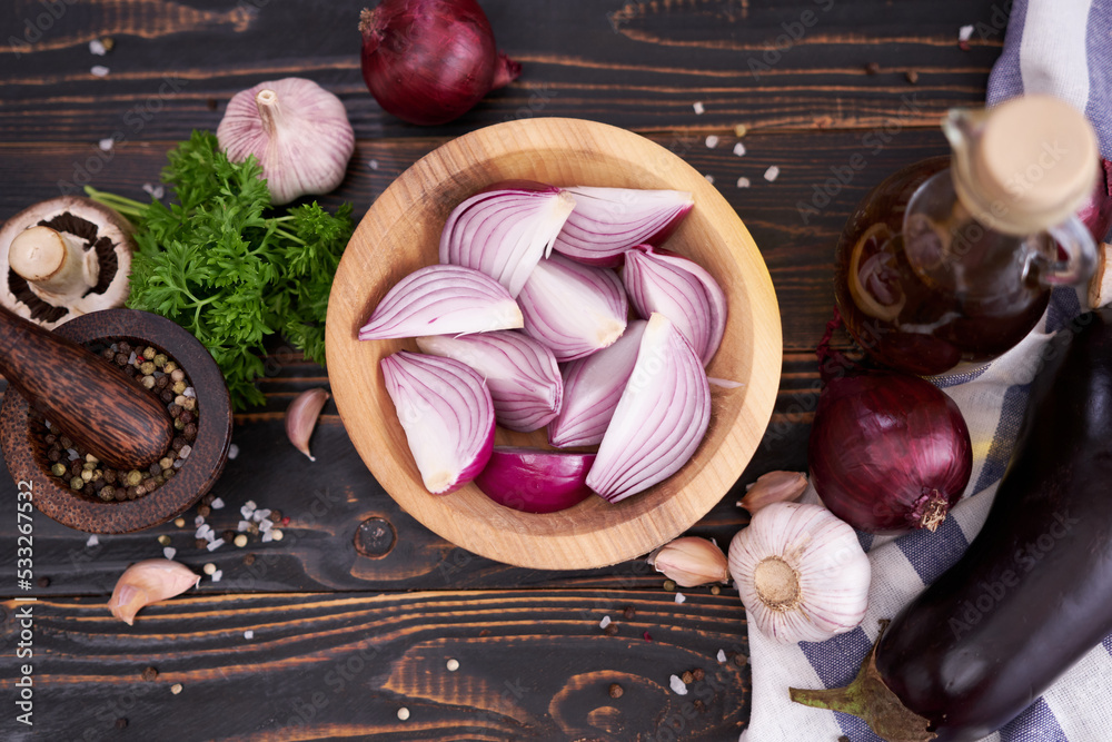Sliced Red Onion in wooden bowl on dark background