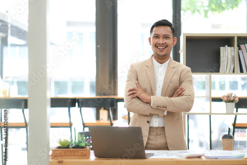 Asian businessman standing by his desk in office