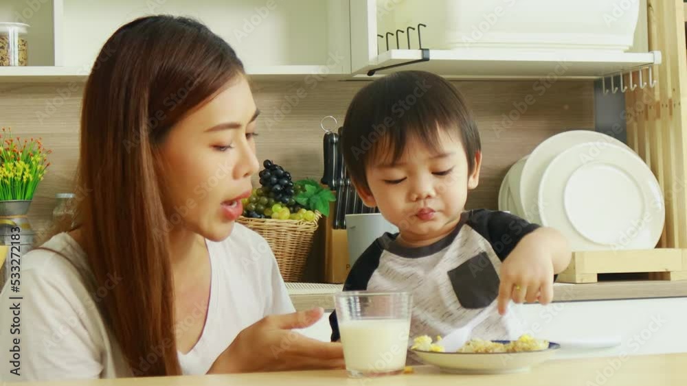 Happy Asian mother and son at home on vacation. boy eating breakfast and drinking milk mother holding her son with love Happy Asian mother and son at home on vacation. boy eating breakfast and drinking milk mother holding her son with love