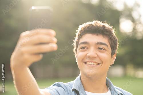 Closeup of hispanic teenager boy taking selfie at sunset or sunrise.