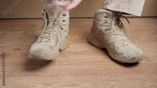 A man laces up brown boots. Tourist putting on hiking boots