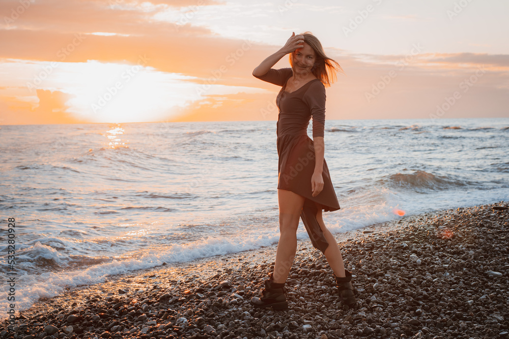 woman dances on the seashore at sunset. Psychology of soul and body dance grace