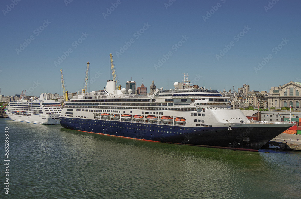 Classic Holland America HAL and Oceania cruise ship or cruiseship liner in port of Montevideo, Uruguay during South America cruising in summer with blue sky and containers and cargo