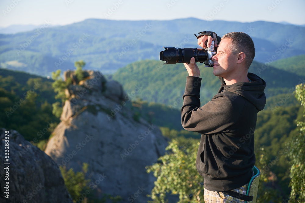 Man photographer with digital camera on top of the mountain in the morning, taking photo of sunset mountains. Concept of travel lifestyle. Man photographer with digital camera on top of the mountain in the morning, taking photo of sunset mountains. Concept of travel lifestyle.