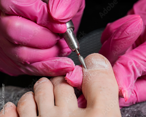 The master makes hardware pedicures to the client. Cuticle treatment. 