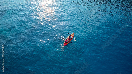 Aerial drone photo of colourful sport canoes as shot from above in turquoise clear sea. High quality photo