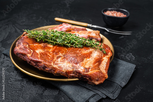 Grilled in BBQ Pork spare Ribs on steel plate with thyme. Black background. Top view