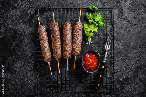 Grilled shish kebab, arabic kofta kofte kebab from mince lamb and beef meat on Skewer. Black background. Top view photo