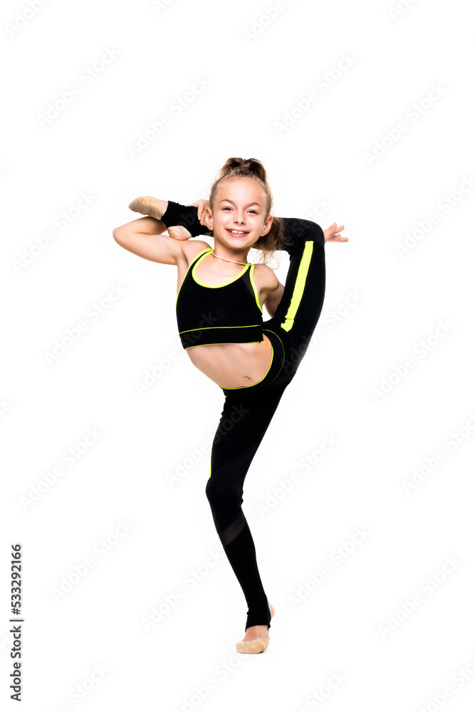 Gymnastic tricks. A flexible little girl gymnast in a sports black suit keeps her balance while standing on one leg and does acrobatic exercises