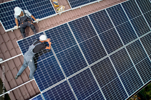 Foto Men workers mounting photovoltaic solar moduls on roof of house