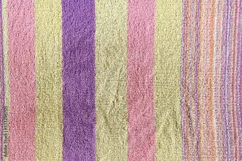 An old terry towel. A natural towel with a nap in stripes of pink, yellow and blue. A used kitchen towel.