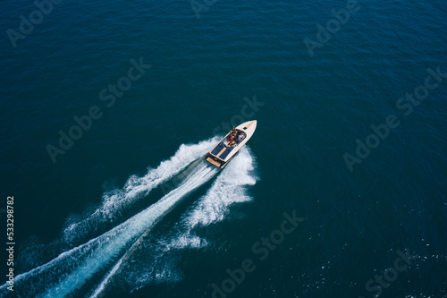 Luxurious boat fast movement on dark water. Luxurious motor boat rushes through the waves of the blue Sea. Boat fast moving aerial view.